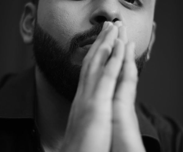 Close-up of a man's hands in a meditative pose, showing focus.