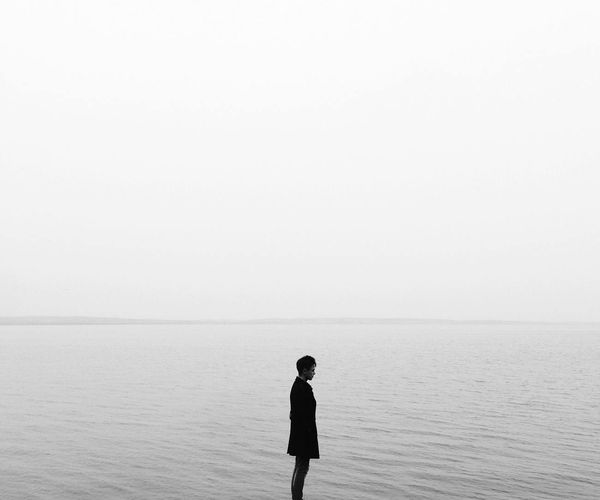 Silhouette of a person standing calmly against a minimal background.
